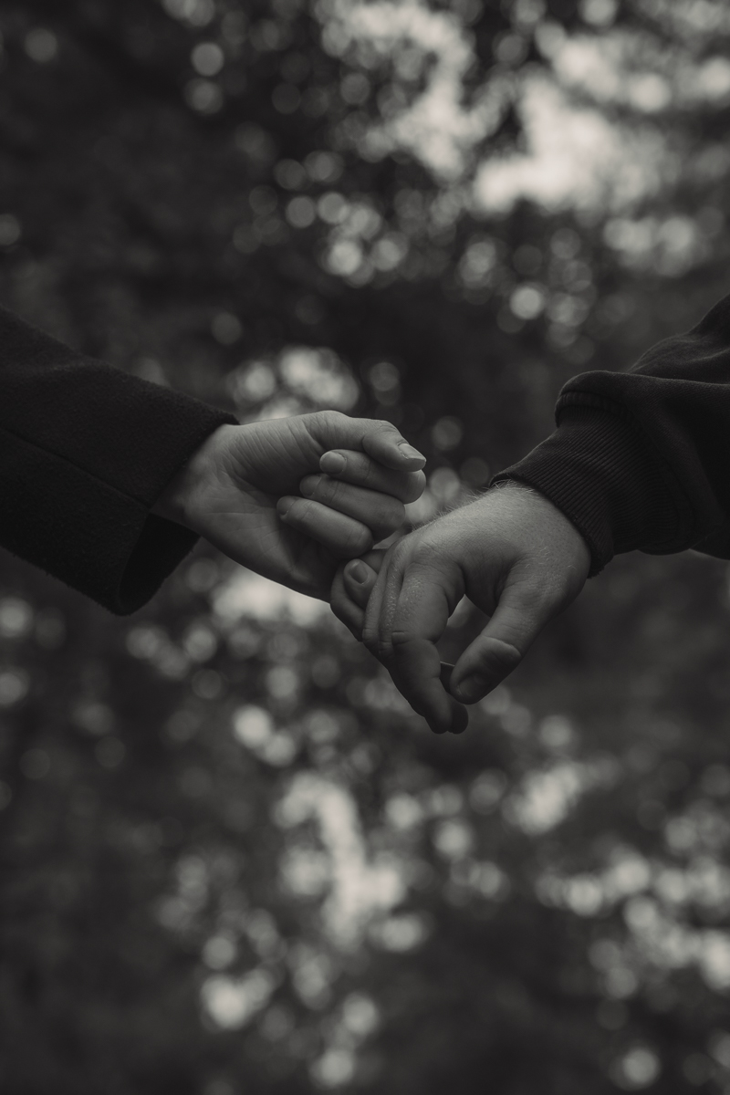 Detailaufnahme von ineinander verschränkten Händen mit Ring während eines Paarshootings in schwarz-weiß.