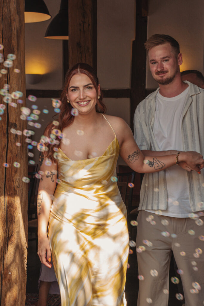 Brautpaar verlässt strahlend die Location, umgeben von Seifenblasen.