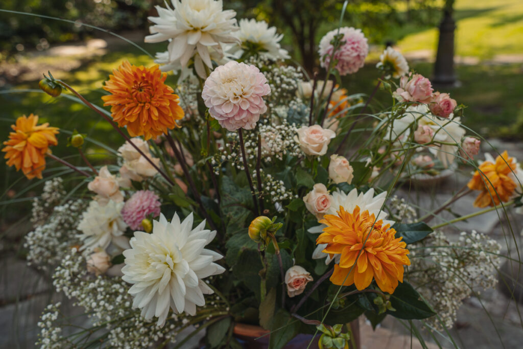 Sommerliche Blumendekoration mit Dahlien bei einer Outdoor-Hochzeit.