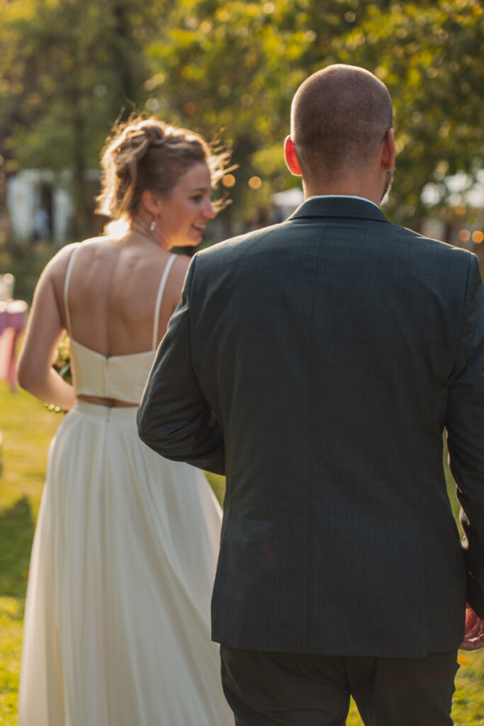 Brautpaar läuft im warmen Abendlicht nebeneinander durch eine Gartenlocation.