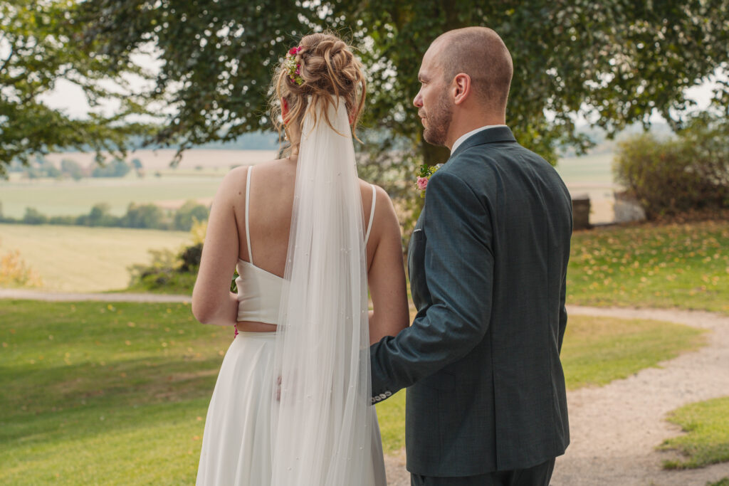 Braut und Bräutigam stehen nebeneinander im Grünen und genießen einen ruhigen Moment nach der Trauung.