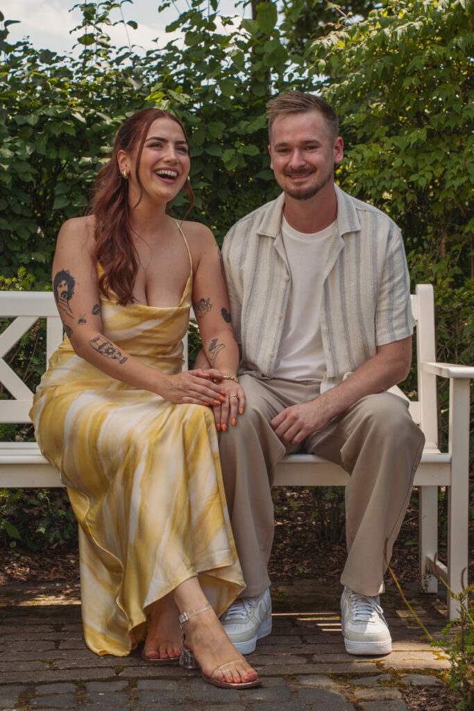 Braut und Bräutigam stehen nebeneinander im Innenraum einer Hochzeitslocation und lächeln.