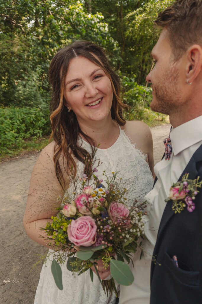 Natürliches Brautpaarportrait im Grünen mit Brautstrauß.