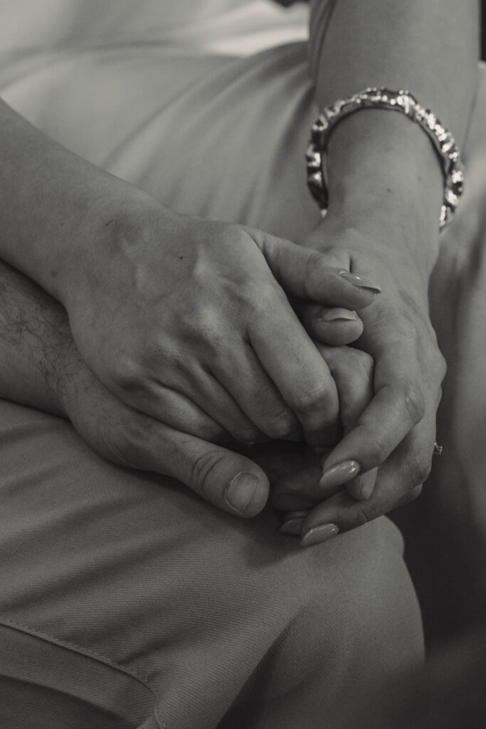 Schwarzweißaufnahme von ineinander verschränkten Händen eines Paares.