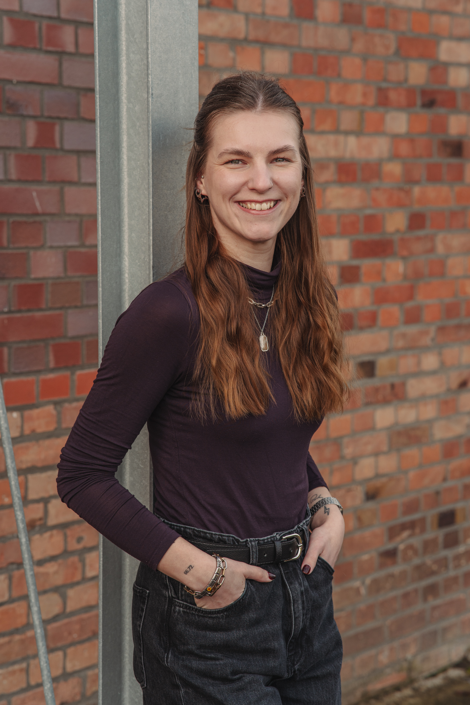 Authentisches Portrait einer Fotografin vor einer Backsteinwand.