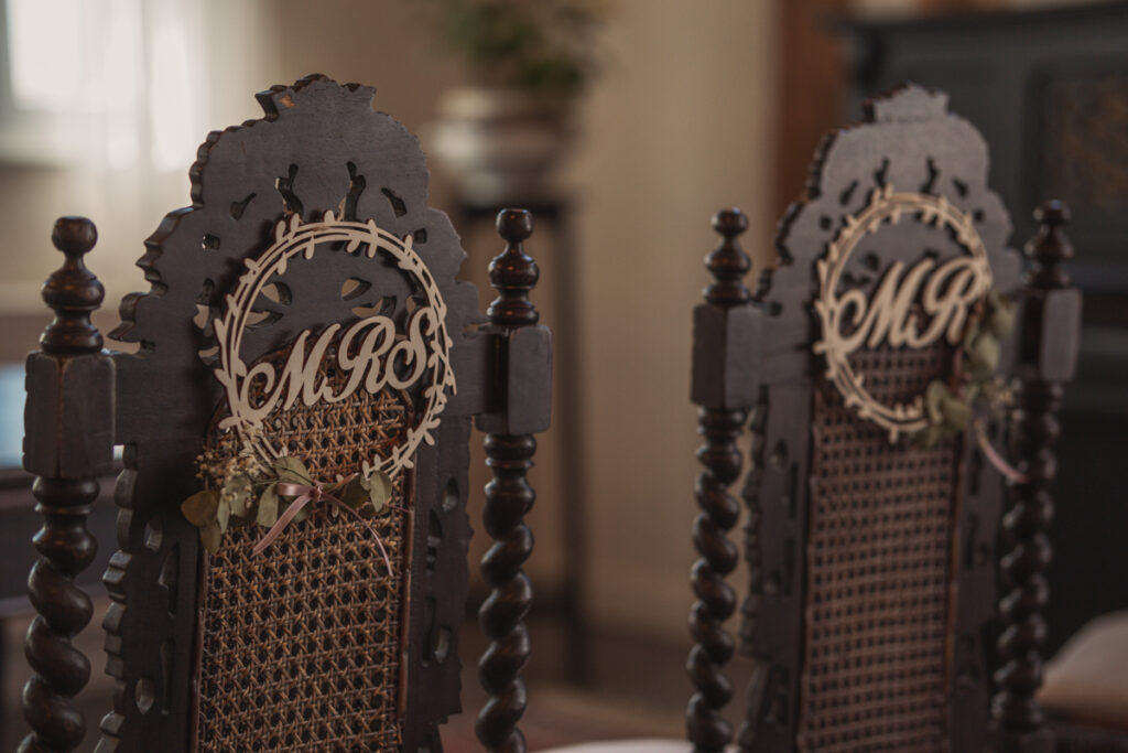 Dekorierte Holzstühle mit personalisierten Namensschildern bei einer Trauung.