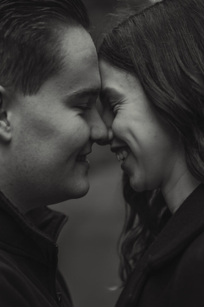 Sehr nahe Aufnahme eines Paares, das sich lächelnd Stirn an Stirn berührt in schwarz-weiß.