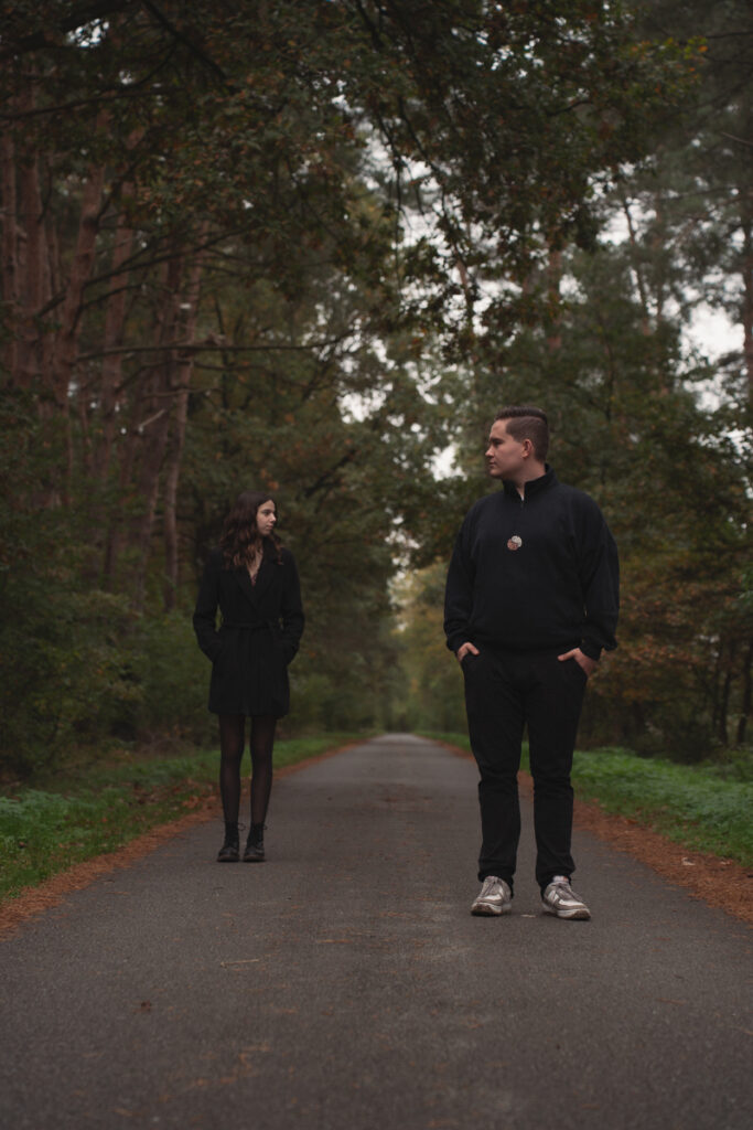 Ein Paar steht sich auf einem ruhigen Waldweg gegenüber und blickt sich an.