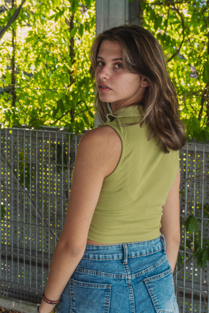 Einzelportrait einer jungen Frau vor grünem Blätterhintergrund im natürlichen Licht. .