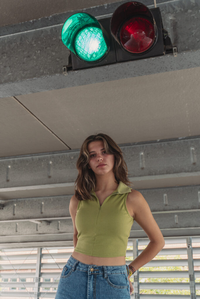 Einzelportrait einer jungen Frau unter einem Parkdeck mit urbanem Hintergrund.