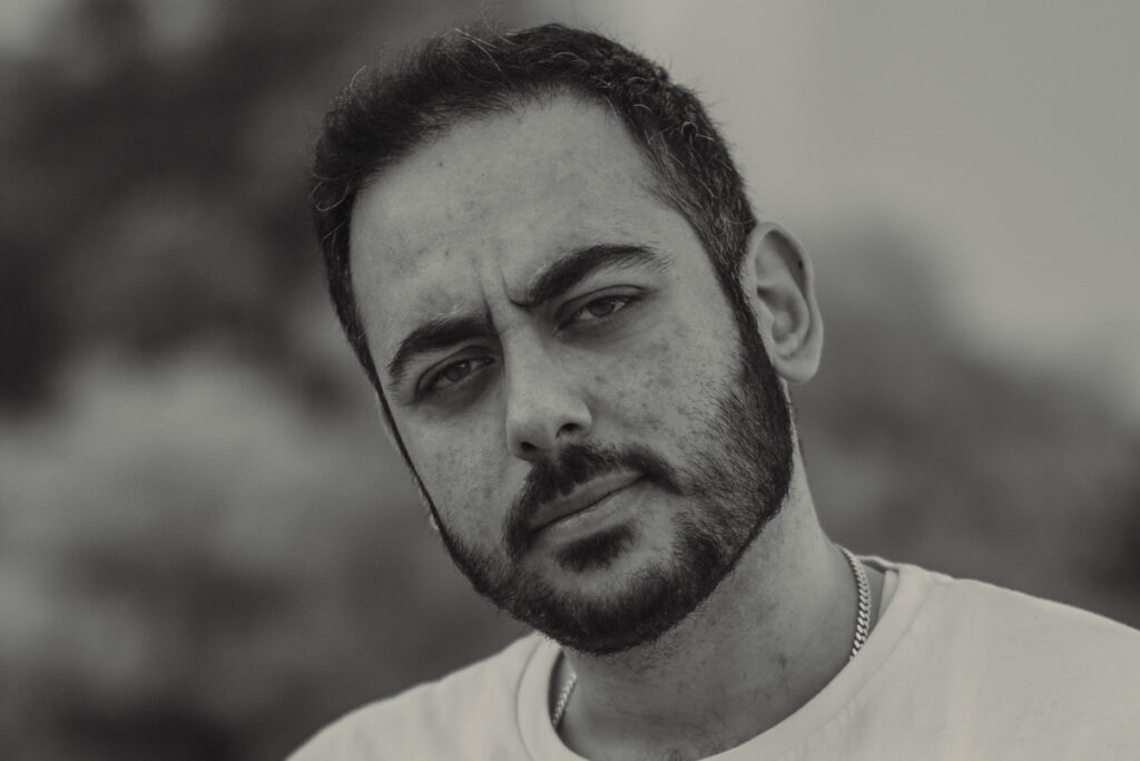 Schwarzweiß-Nahaufnahme eines Mannes mit ruhigem, direktem Blick in die Kamera.